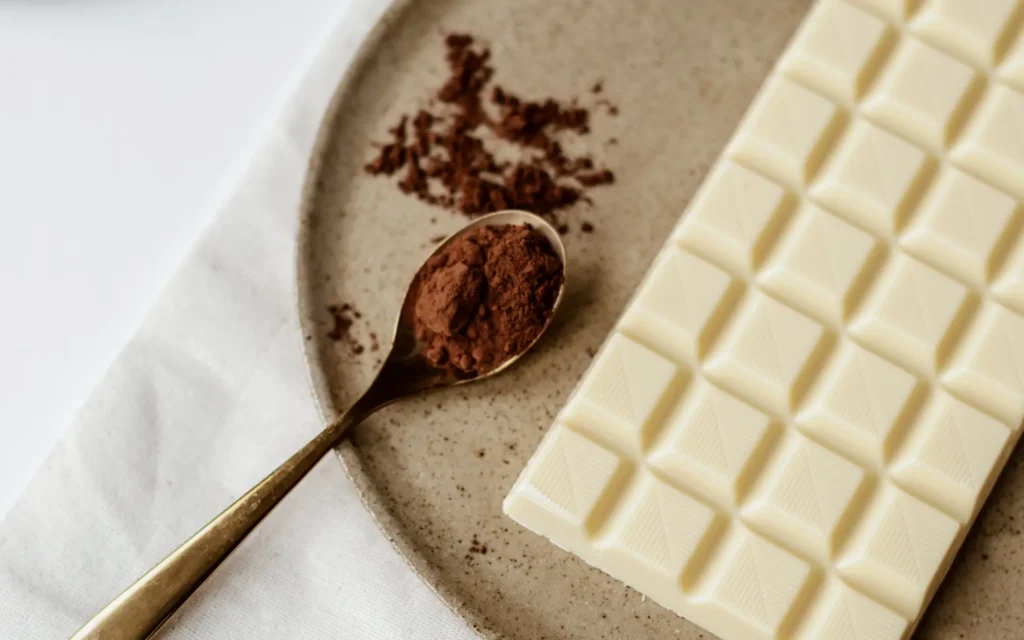 A spoon of cocoa next to a bar of white chocolate, signifying taste and smell experienced in dreams.
