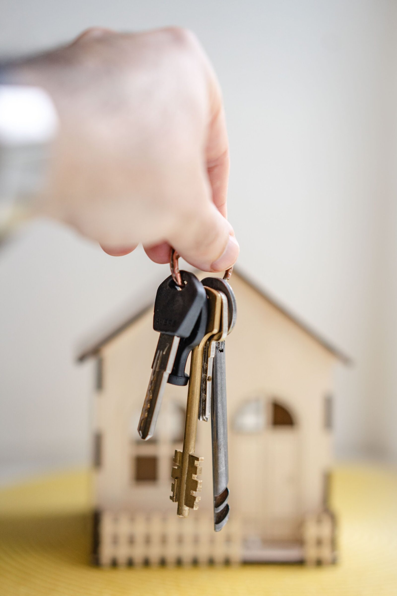 Keys being held in front of a model house symbolizing mortgages