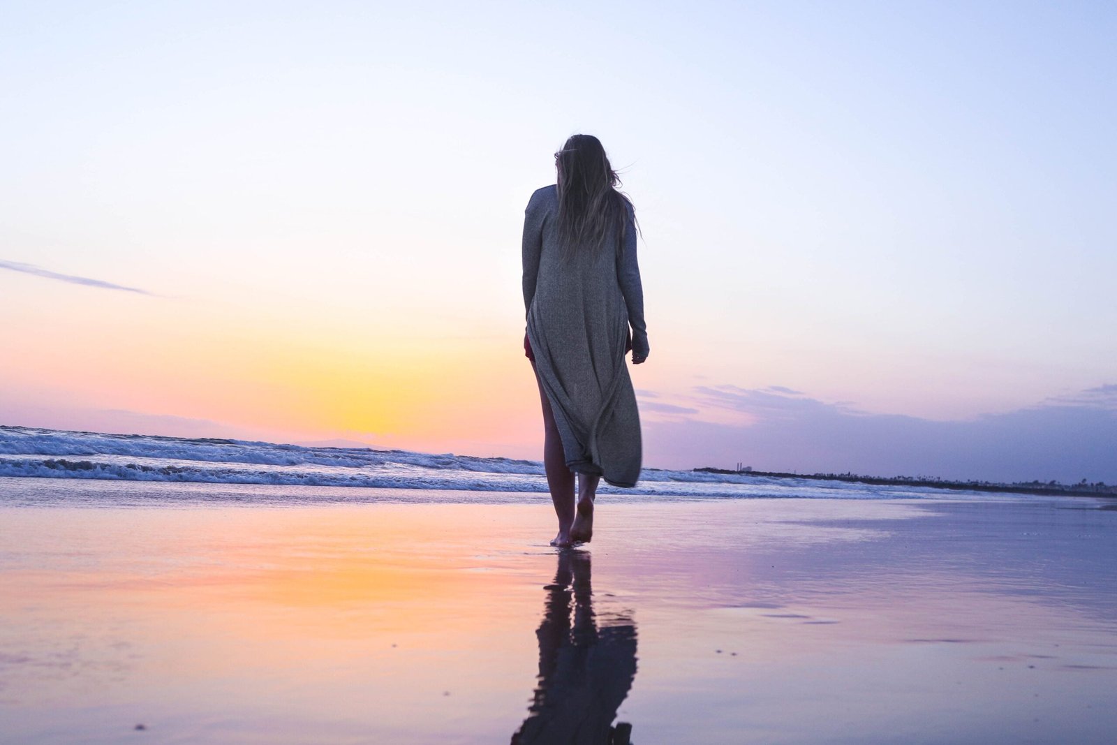 A woman walking down a beach just before sleep