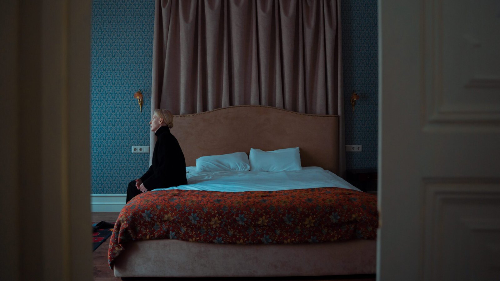 A depressing scene of a woman sitting on her bed.
