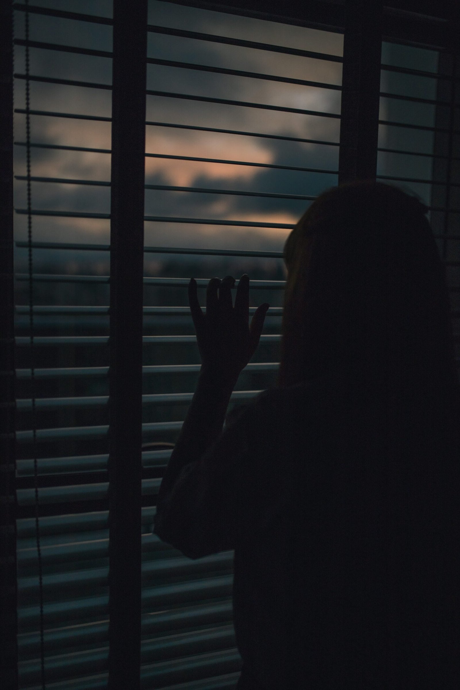 A woman peeking out of a window - signifying emotional stress or unease