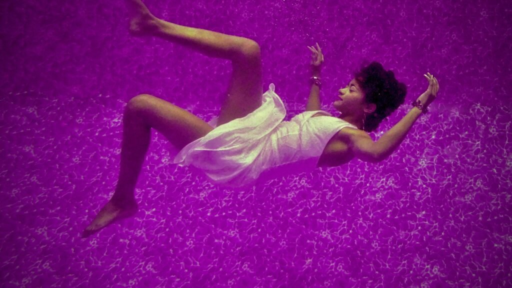 A woman floating in a purple dreamlike liquid