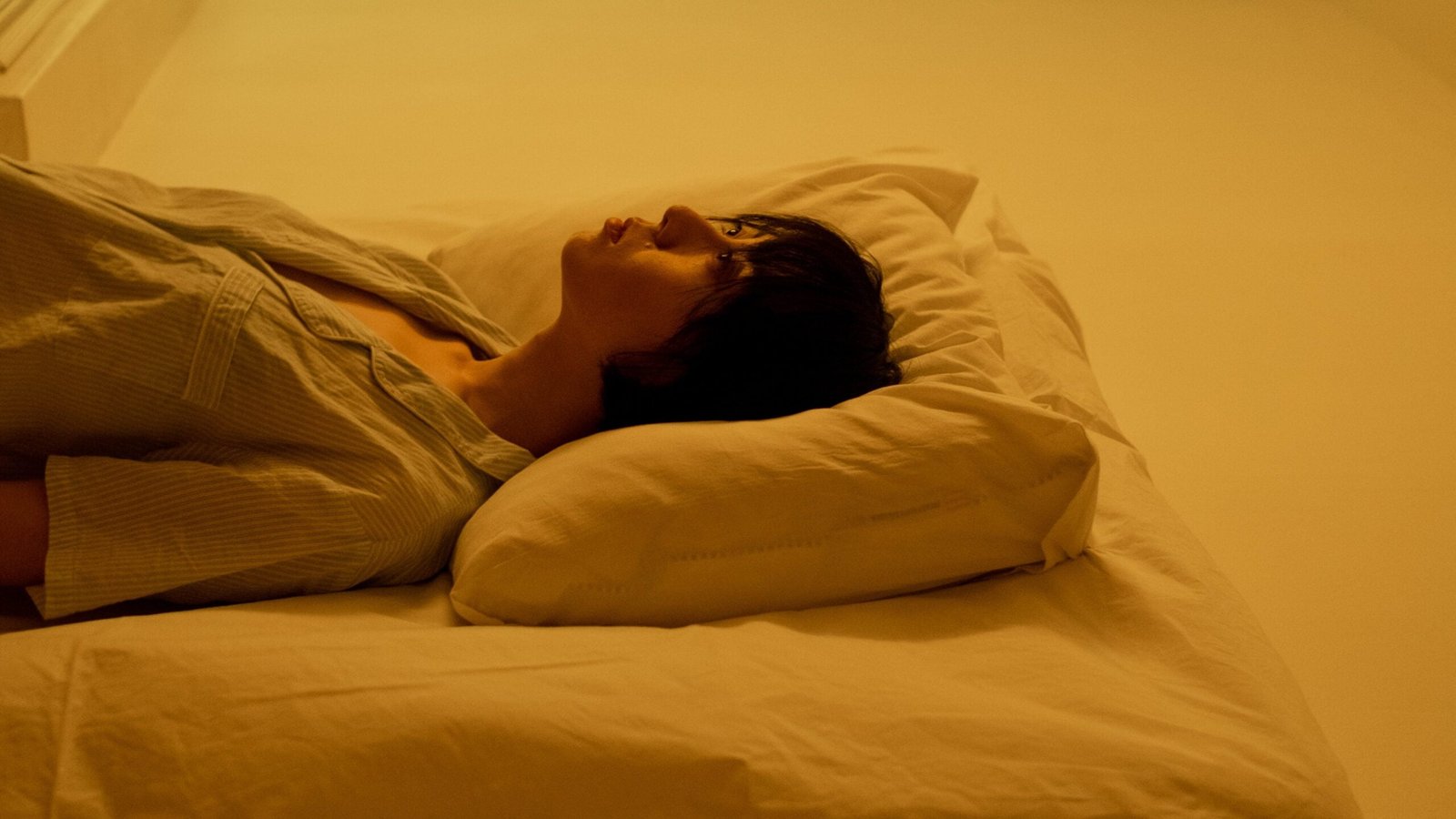 A woman lying comfortably on a pillow practicing sense initiated lucid dreaming
