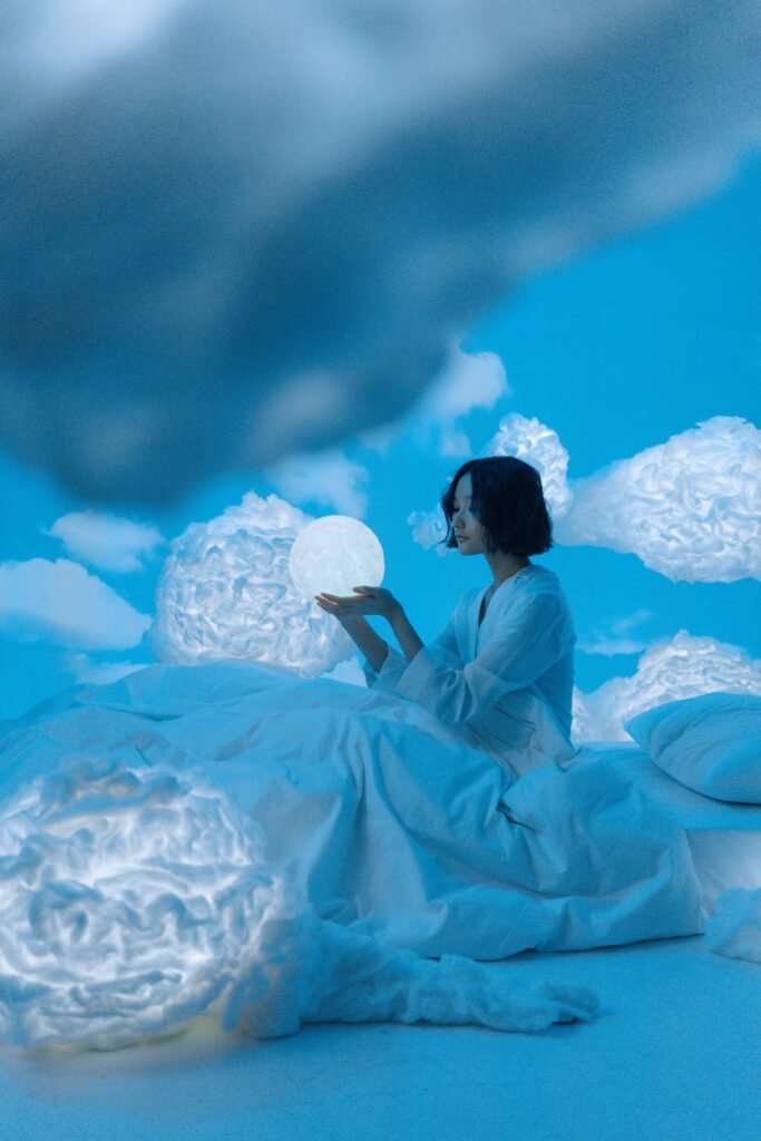 A woman sitting in her bed holding a glowing sphere, illustrating the possibilities of lucid dreaming