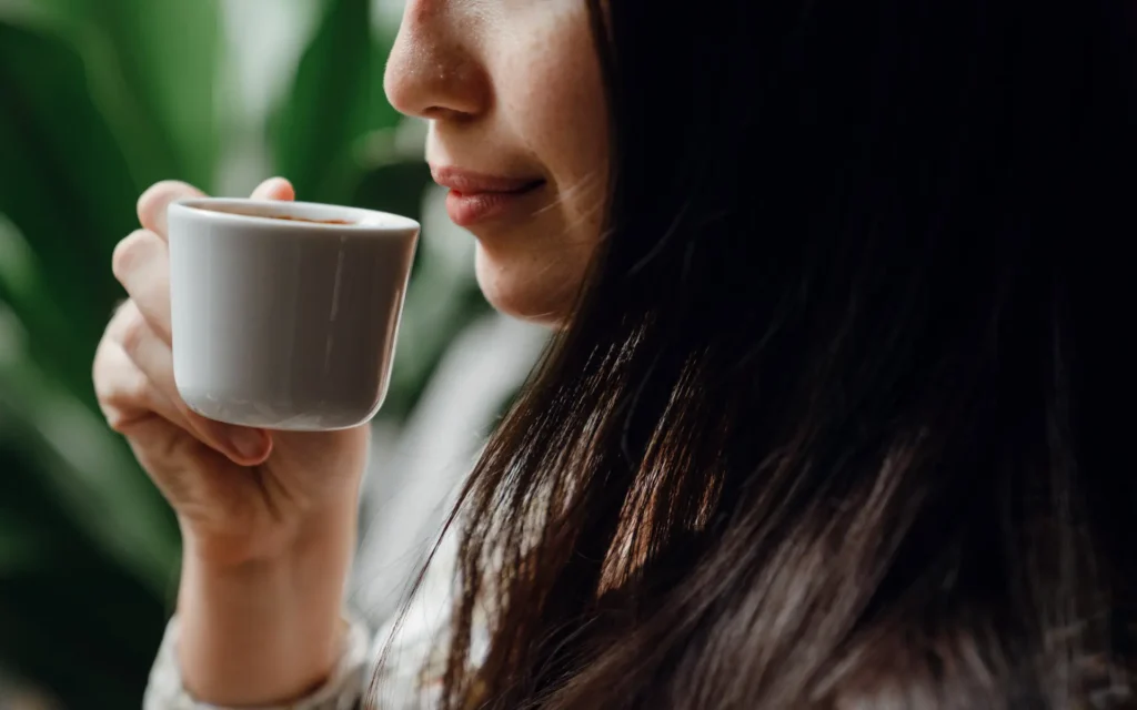 A woman holding a cup of coffee close to her nose, signinfying the role of taste and smell in dreams.